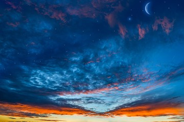 Fototapeta premium Moon in bright clouds of sunset sun . New moon