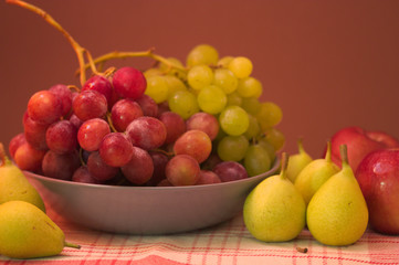 Still life of fruit with grape, pears, apples with brown background