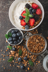Healthy breakfast with granola, yogurt, fruits, berries on dark metal background. Summer homemade breakfast.