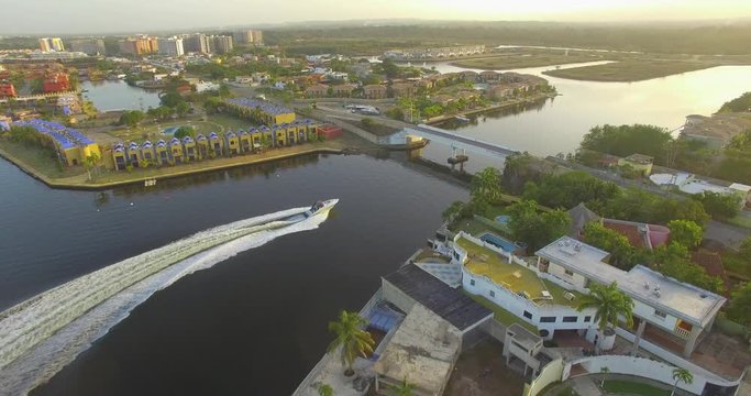 Aerial view of a fast boat in the Higuerote canals , in Venezuela, sailing under the bridge in the golden hour
