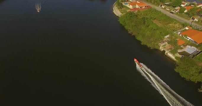 Drone following a small red fishing boat on a canal in Higuerote, Venezuela