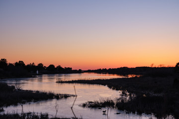 Naklejka premium Winter ice on a winding salt pond cove under a brilliant sunset