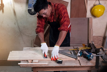 Handsome man wearing protective glasses and gloves,standing beside tools and equipment for doing...