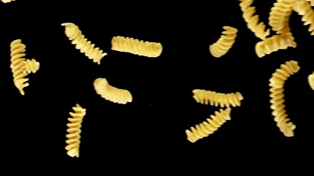 Super slow motion of flying uncooked italian pasta fusilli on black background. Filmed on high speed cinema camera, 1000 fps.