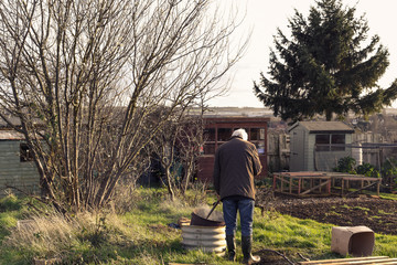 Man having a bonfire at an allotment or community garden vegetable plot to dispose of garden waste