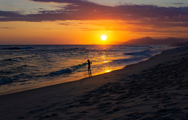 Fototapeta na wymiar Silhouette Of Child Playing On Exotic Beach With Beautiful Sunset 