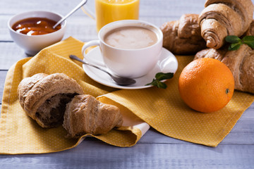 breakfast with fresh croissants and coffee on wooden table