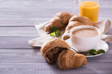 breakfast with fresh croissants and coffee on wooden table