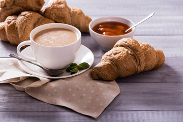 breakfast with fresh croissants and coffee on wooden table