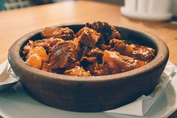 Close up of hot beef stew served in clay bowl.