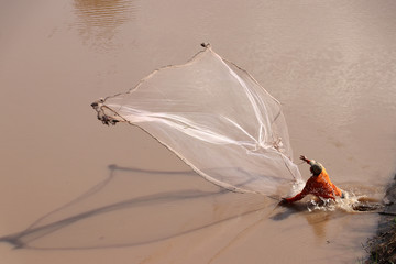 A fisherman throwing a net into the river.