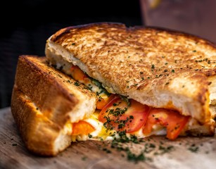 sandwich de pan brioche y queso fundido con tomates cherry y cebollin con salsa picante de chiles 