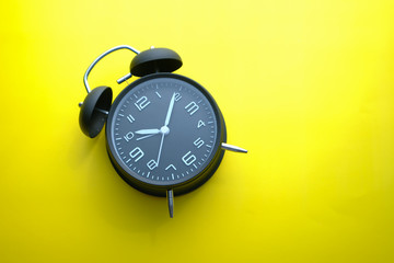 top view of alarm clock on yellow background 