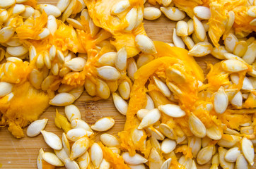 orange pulp of ripe pumpkin with white seeds on a wooden background