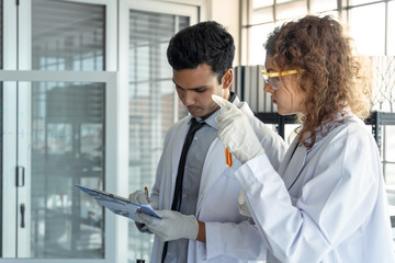 Research scientists in white coats working in modern biological laboratory.