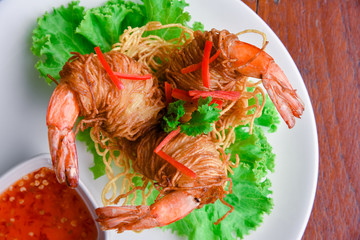 Goong Sarong  noodles Wrapped Shrimp With Crispy Noodle Serve, vegetable and sauce in white plate  on wood table , Thai food