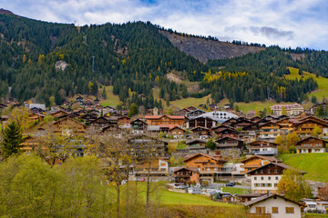 Traditional Swiss style houses on the green hills with forest in the Alps area of Switzerland, Europe