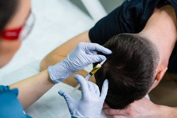 Injection plasma into head hair man cosmetologist doctor