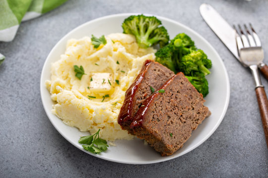 Meatloaf with spicy glaze sliced on a plate with mashed potatoes and broccoli, ground beef and pork dish