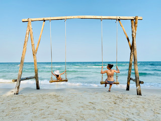 Mädchen und Frau auf Schaukel am Meer