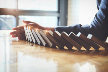 Business risk control concept, Businessman protect wooden block fall to planning and strategy in...