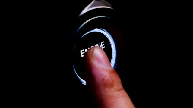 The driver's hand is pressing the car start button. Concept of transportation and technology
