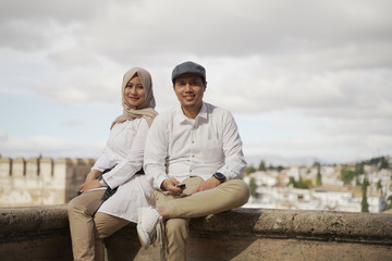 Stylish Asean Muslim couples enjoy the view in the corner of the famous traditional Islamic Alhambra building in Spain during the day