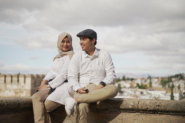 Stylish Asean Muslim couples enjoy the view in the corner of the famous traditional Islamic Alhambra building in Spain during the day