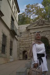 Fototapeta na wymiar Asean young moslem woman wearing beige hijab stylish take a picture at the Colonnade in the courtyard of Charles V palace. Alhambra Site. Granada, Andalusia, Spain