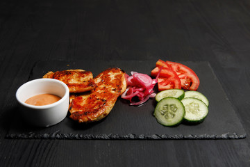 Grilled chicken pieces with vegetables on a table.