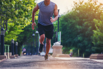 Man running sprinting on road. Fit male fitness runner during outdoor workout in the park. Selected...