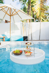 Fototapeta na wymiar Breakfast and afternoon tea set floating around swimming pool