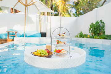 Fototapeta na wymiar Breakfast and afternoon tea set floating around swimming pool