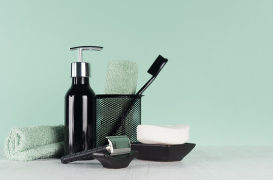 Stylish mint menthe bathroom interior with bath cosmetic - black razor, toothbrush, towel, dispenser soap on soft light white wood table.