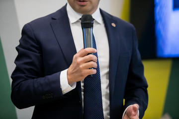 Young talking man holding microphone without confidence on isolated white background