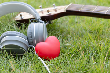 Love music. Red heart and headphones music and guitar classic on green fields. Sound of life. Acoustic music.