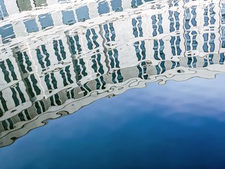 reflection of a residential building and blue sky on the water surface of city river embankment