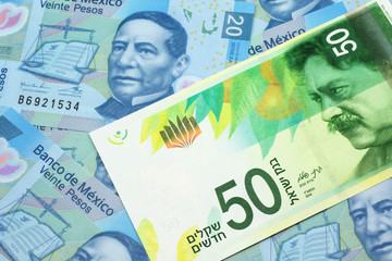 Fototapeta premium A close up image of a fifty shekel bank note from Israel on a background of Mexican twenty peso bank notes in macro