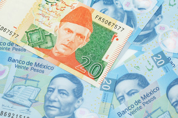 A close up image of an orange and green twenty Pakistani rupee bank note with Mexican twenty peso bank notes in macro