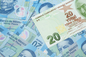 A close up image of a green twenty Turkish lira bank note on a background of Mexican twenty peso bank notes in macro