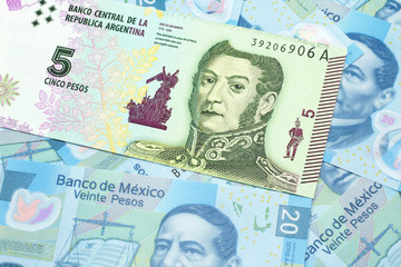 A five peso bank note from Argentina on a background of Mexican twenty peso bank notes close up