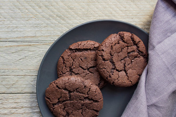 Top view of homemade chocoate cookies on black plate on wooden background. Home bakery