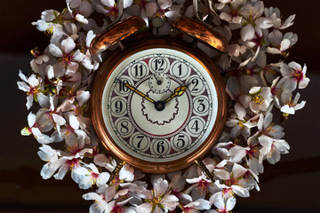 Vintage alarm clock surrounded by white and red flowers