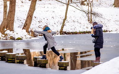 Two girls cross a river in a winter Park