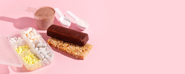 Protein powder, scoop, energetic musli bars, vitamin pills, gainer on pink background with shadow - concept of sport diet, healthcare, nutrition fit fitness food, copyspace
