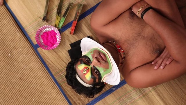 Kathakali dancer lying on the chatai and looking upwards. 