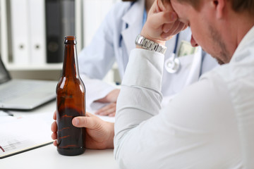 Alcoholic hold in hand empty bottle at doctor reception office closeup. Grief and despair,...