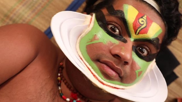 Close up of a Kathakali dancer lying on the chatai and looking upwards. 