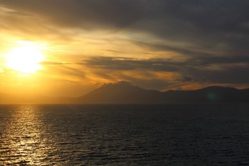 evocative image of sunset over the sea with headland silhouette in the background
