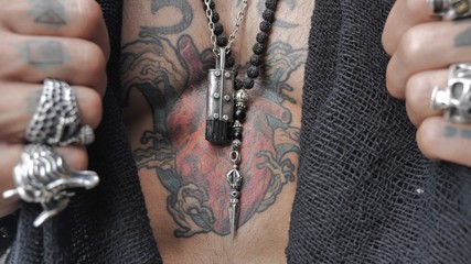 male hands open a heart-shaped tattoo on the chest